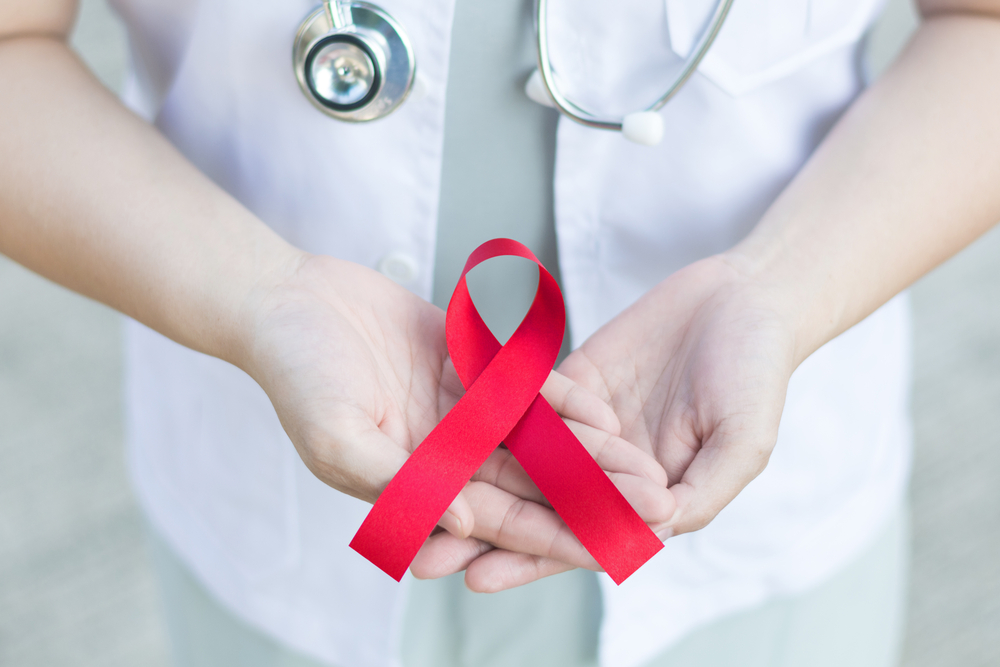 Female,Doctor,In,White,Uniform,With,Red,Awareness,Ribbon,In